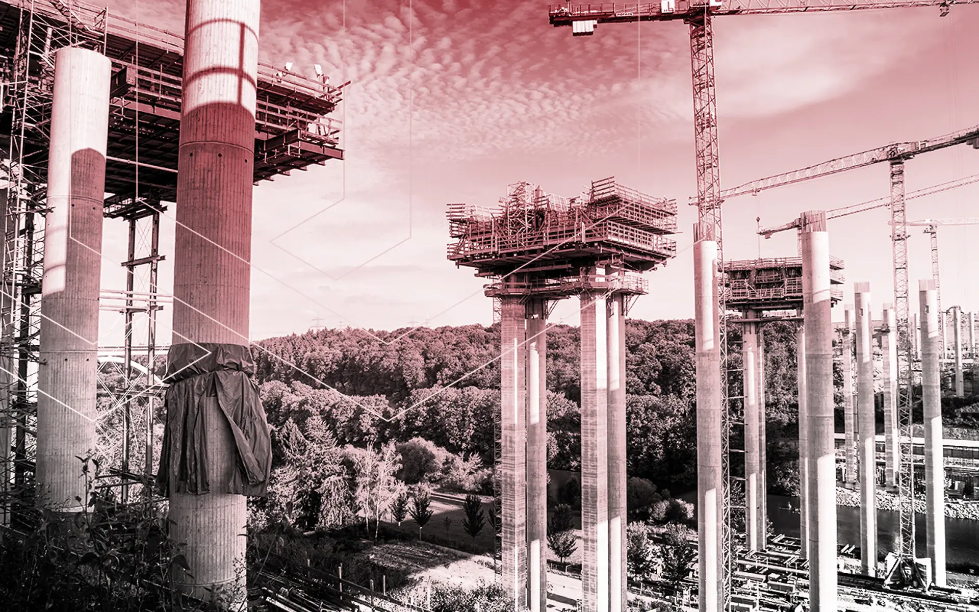 Brückenbaustelle mit hohen Betonpfeilern, Schalungsgerüsten und Baukränen